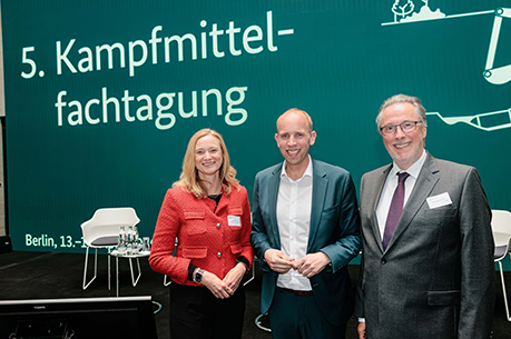 Drei Personen vor einem Banner