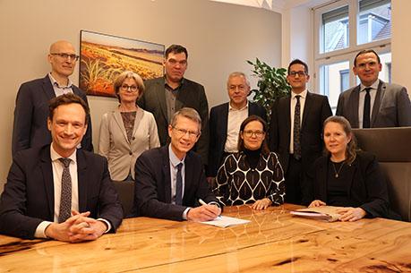 Nach der Unterzeichnung des Kaufvertrags in Schweinfurt (sitzend von links nach rechts: Landrat Florian Töpper, Verbandsvorsitzender Oberbürgermeister Sebastian Remelé, Larissa Komnick (BImA), Notarin Bianca Muschel; stehend von links nach rechts: Frank Deubner (Geschäftsleitung des Zweckverbands), Bürgermeisterin Bettina Bärmann, Bürgermeister Thomas Hemmerich, Otto Mayr (BImA), Christian Boll (BImA), Tobias Blesch (Geschäftsleitung des Zweckverbands))