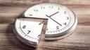 Eine silberne Uhr mit weißem Zifferblatt liegt auf einem Holztisch, das linke untere Viertel ist herausgeschnitten und ein kleines Stück versetzt