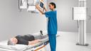 Technologist adjusting the low tube touchscreen above a patient lying on the table