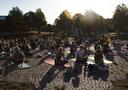 People sitting on yoga  mats at the University of Bayreuth with the sun setting in the background