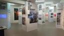 „Ausstellungsraum mit mehreren hohen Infopaneelen zu Stadtplanung und Modernisierung. Die Tafeln zeigen Texte, Fotos und Karten zu Themen wie Gegenwartsstadt, Wohnhöfe, Planstädte und Wohnen nach Norm.