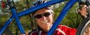 Ein Mann mit Helm und Sonnenbrille hält ein blaues Fahrrad vor sich