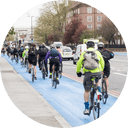 People riding bikes on a bike lane next to a street in a city