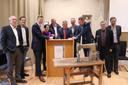 Gruppe von Menschen in formaler Kleidung um ein Stehpult herum. Sie lächeln locker in die Kamera und unterzeichnen ein Dokument.