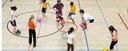 Schülerinnen und Schüler beim Sportunterricht in einer Turnhalle spielen ein Ballspiel