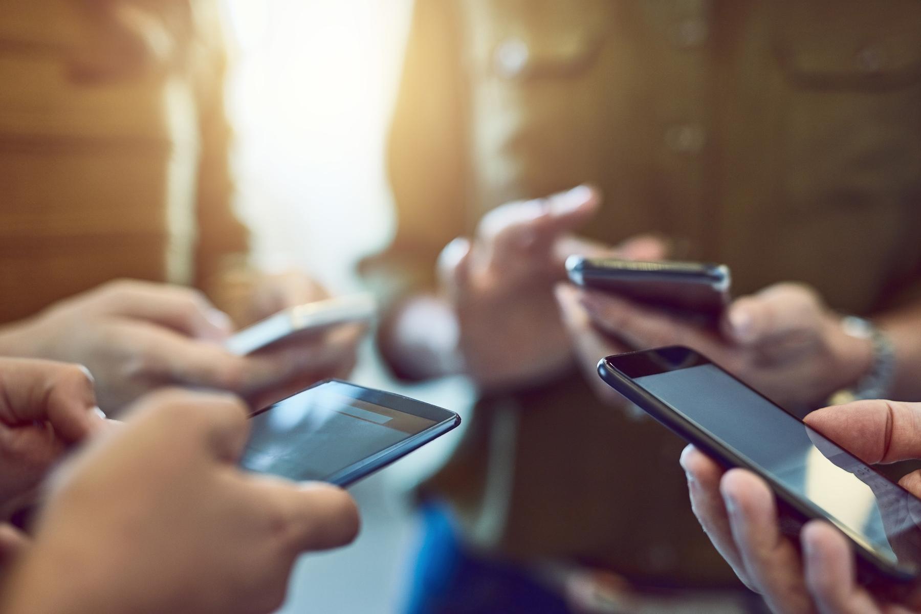 dl-med ntii Personen stehen im Kreis und halten ihr Handy's in der Hand