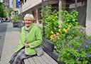 Eine Frau sitzt auf einer Bank neben blühenden Pflanzen