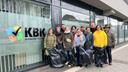 Elf Mitarbeitende des KBK stehen mit Müllsäcken und Zangen ausgestattet vor der Glasfront des Kundencenters