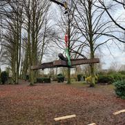 Ein Metallkreuz hängt an einem Kran auf einem Friedhof