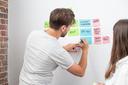 Zwei Menschen vor einem Whiteboard mit Post-its