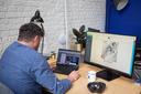 A man sits in front of a desk and the e-mail builder is displayed on the notebook and desktop monitor