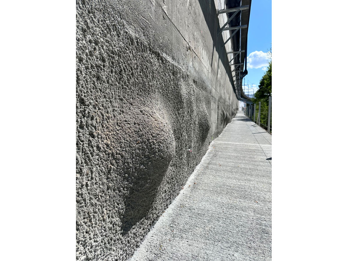 Detailaufnahme einer ausgeführten Spritzbetonwand entlang eines schmalen Unterhaltswegs bei der Hangsicherung Lorraine in Bern.