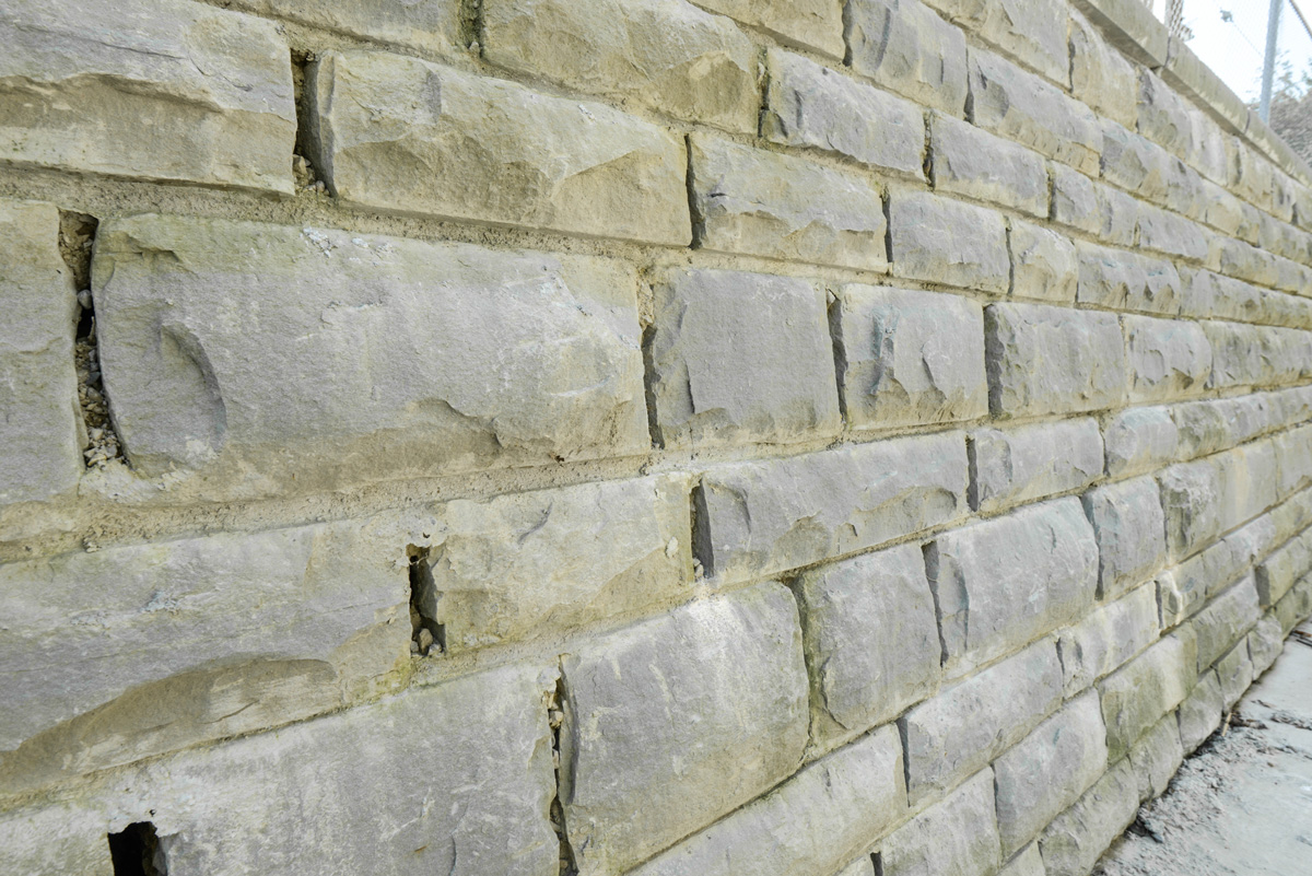 Detailaufnahme der Bachmauer aus Sandstein mit humusgefüllten Fugen zur Förderung der Biodiversität