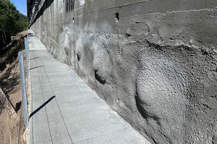 Blick entlang der permanenten Spritzbetonwand mit Unterhaltsweg und Geländer im Projekt Hangsicherung Lorraine.