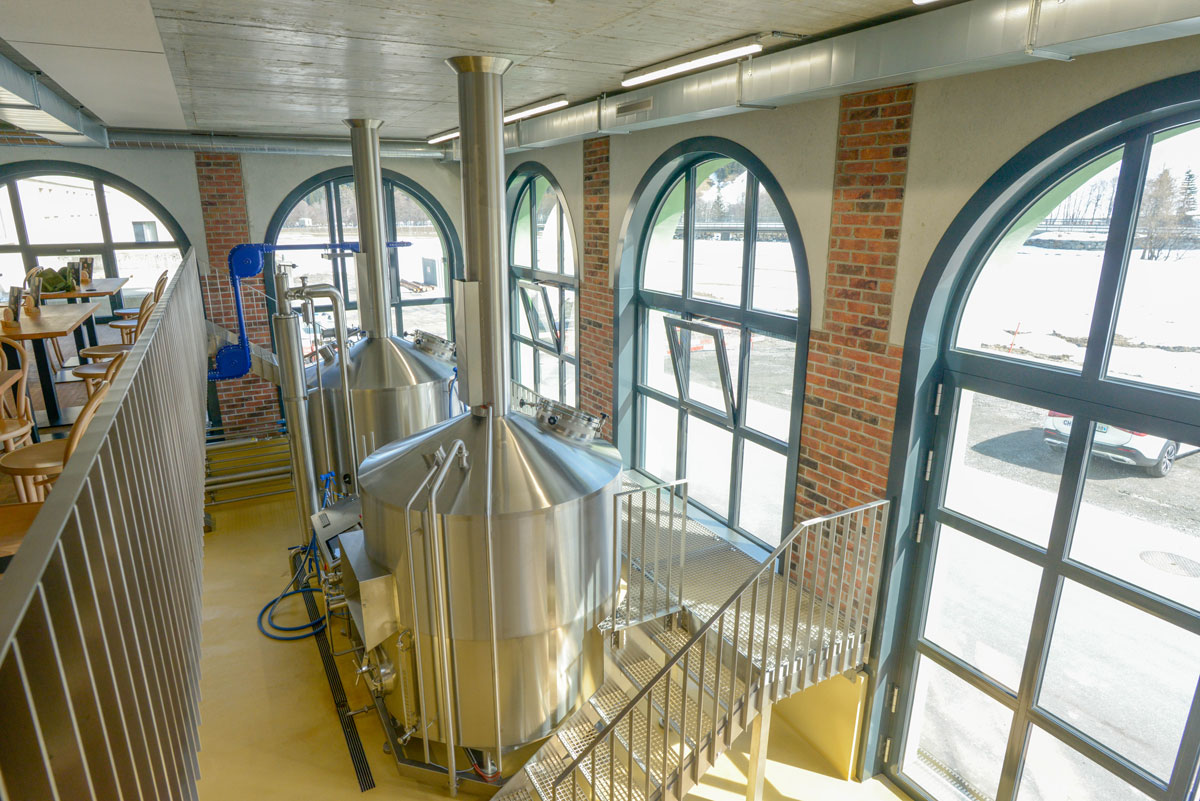 Innenraum der Speluca Brauerei in Sufers mit Sudkesseln, Rundbogenfenstern und Sichtmauerwerkdetails.
