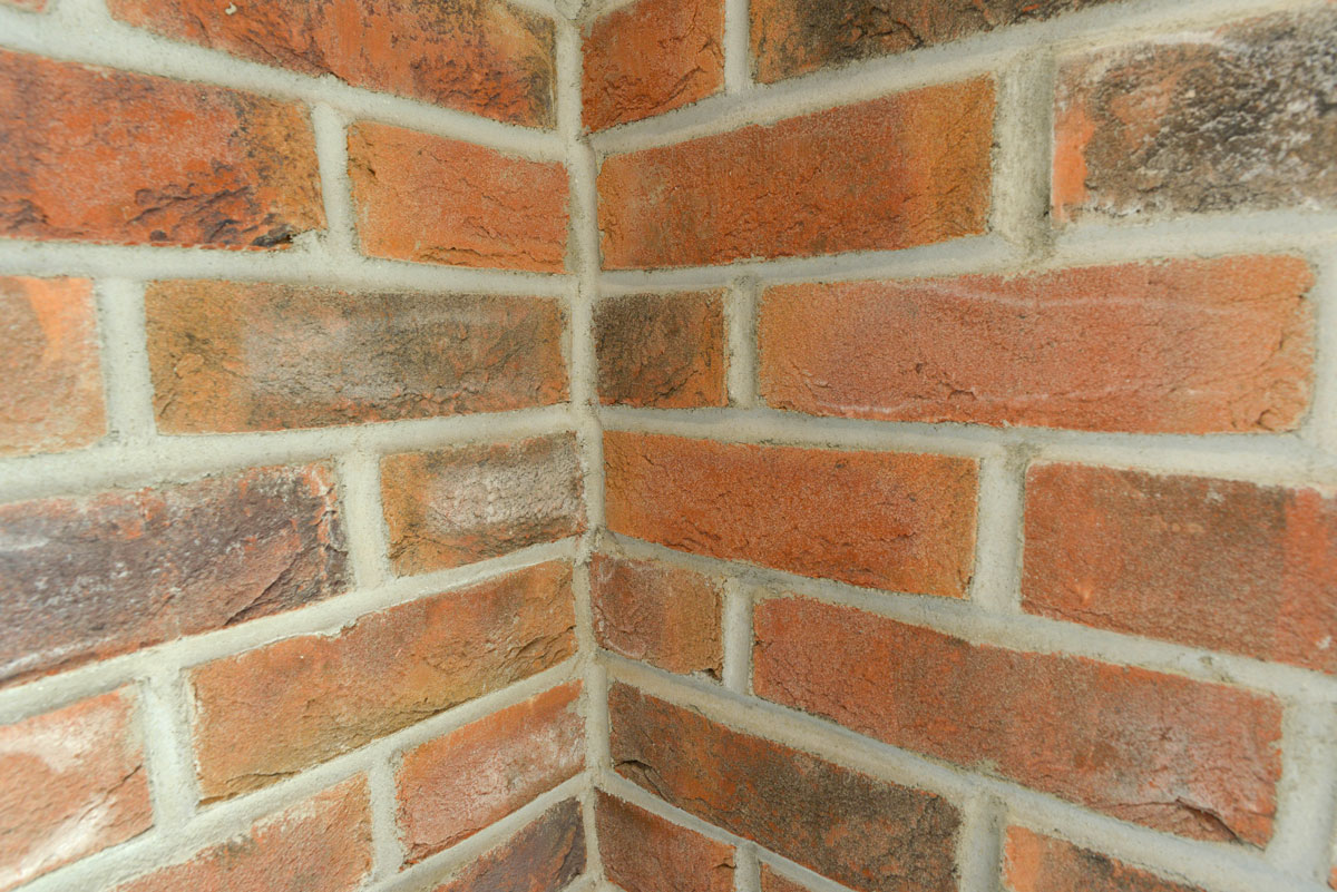 Detailaufnahme einer Mauerecke mit rotem Sichtmauerwerk und hellen Fugen.