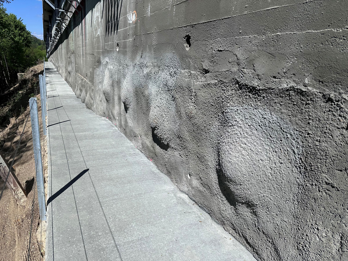 Blick entlang der permanenten Spritzbetonwand mit Unterhaltsweg und Geländer im Projekt Hangsicherung Lorraine.
