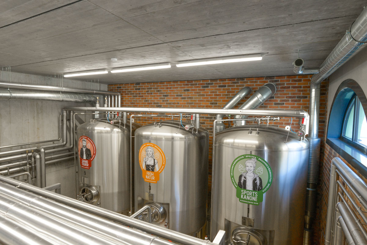 Edelstahl-Gärtanks der Speluca Brauerei vor einer Wand aus rotem Sichtmauerwerk.
