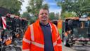Ein Mann steht in einer orangefarbenen BSR-Jacke vor Kleinkehrmaschinen und lächelt in die Kamera.