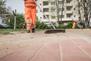 Reinigungskraft der BSR fegt Weg auf einem Spielplatz