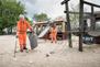 BSR-Einsatzkräfte säubern eine Sandfläche auf einem Spielplatz