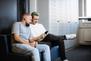 Zwei IT-Fachkräfte der IT sitzen auf einer Couch und schauen auf ein Smartphone