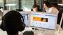 Drei Menschen schauen in einem Großraumbüro in verschiedene PC-Bildschirme.