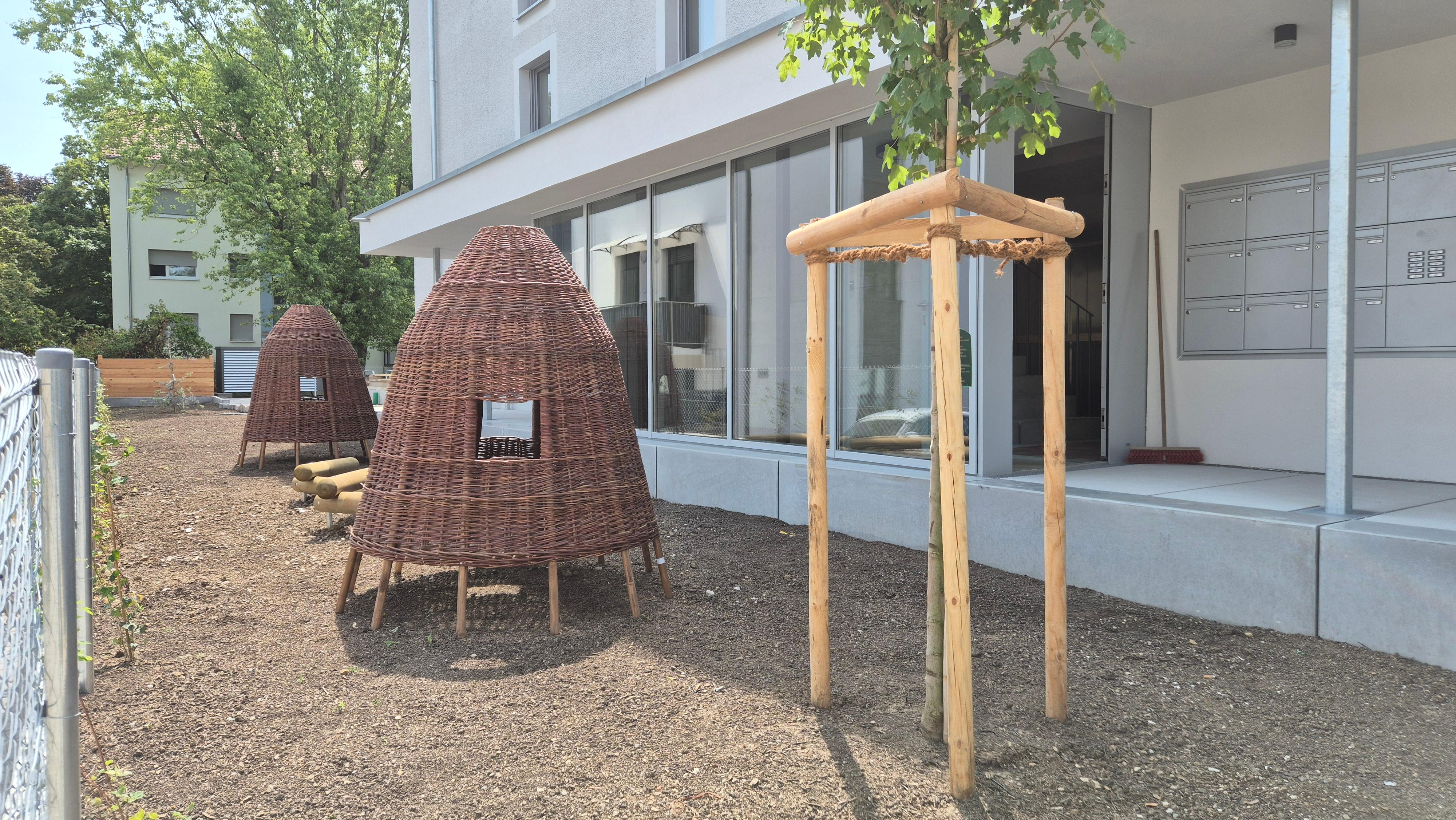 Foto einer Außenanlage mit Strohhäussschen und Jungbaum