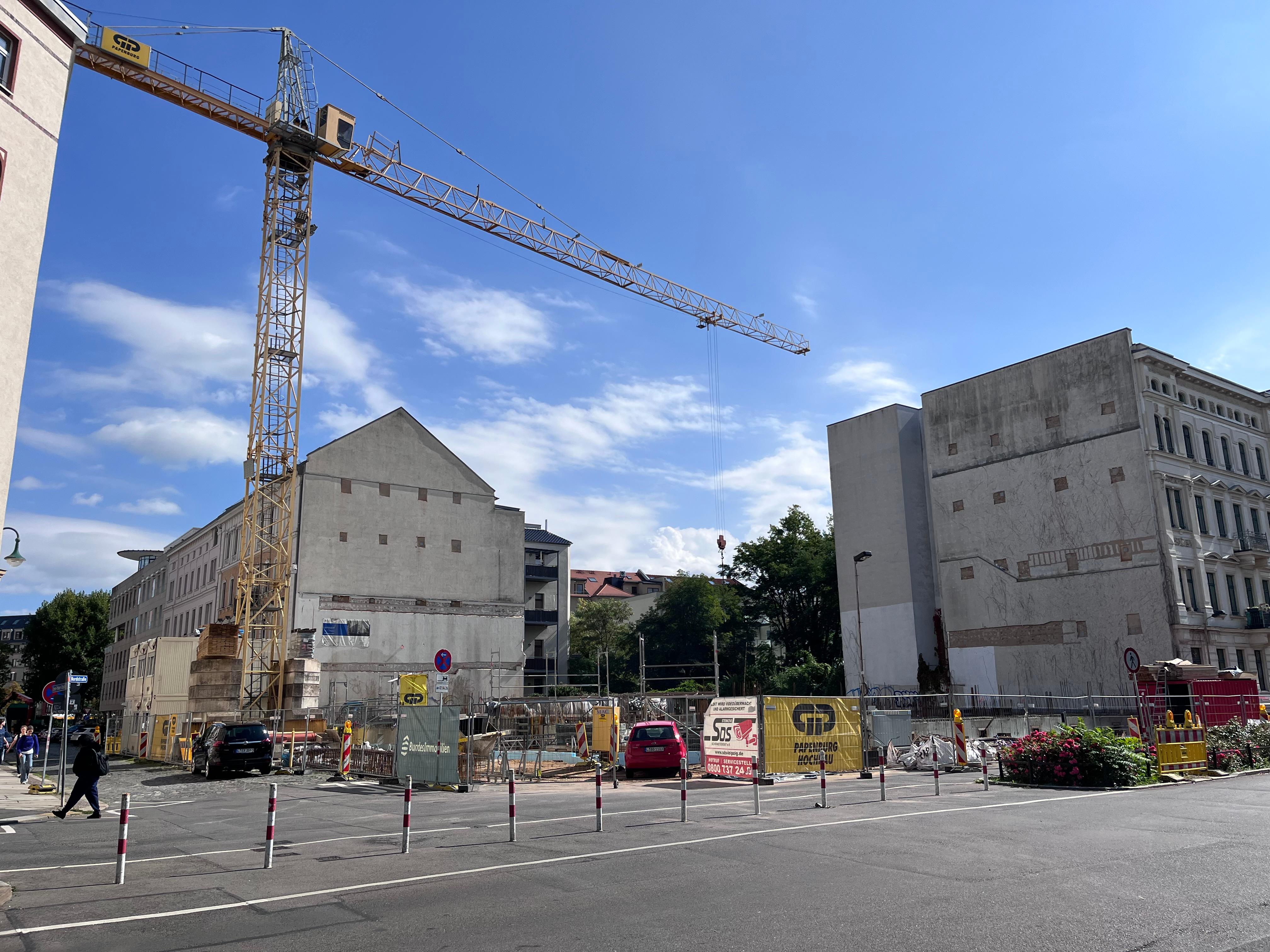 Blick auf zwei Wohnblöcke an einer Eckstraße mit Kränen.