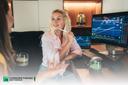junge Dame mit Stift in der Hand, sitzt vor einem Computer auf dem Trendlinien angezeigt werden. 