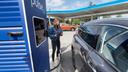 Astrid Drechsel-Grau neben dem E-Auto an einer Tankstelle stehend.