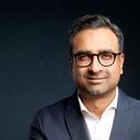 Karun, Mitarbeitender von Consors Finanz, trägt eine Brille, weißes Hemd und blauen Anzug-Sakko und schaut lächelnd in die Kamera.