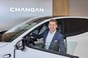 Steffen Obst, Head of Sales, schaut lächelnd in die Kamera. Er trägt einen Anzug und sitzt in einem weißen Elektroauto mit offener Fahrertür. Im Hintergrund ist das Changan-Logo zu erkennen.