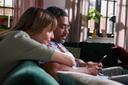 Ein Mann und eine Frau sitzen auf dem Sofa und schauen in ein Smartphone