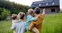 Familie auf einer Wiese vor einem Haus