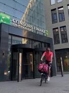 Consors Finanz Mitarbeiter Daniel mit seinem Jobrad vor einem Bürogebäude von Consors Finanz.