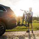 Mann hebt Fahrrad auf den Träger seines Autos