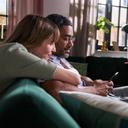 Ein Mann und eine Frau sitzen auf dem Sofa und schauen in ein Smartphone