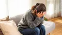 Woman sitting on the sofa and burying her face in her hands