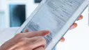 Arzt füllt Formular an Tablet aus