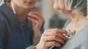 Eine Ärztin hört mit dem Stethoskop eine ältere Patientin ab