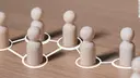 Wooden figures are placed on a wooden panel in marked circles connected by lines.