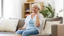 Older lady sitting on a sofa, talking on the phone 