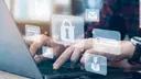 Hände tippen an Laptop mit verschiedenen Icons