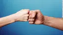 Two fists bump together in a fist greeting against a blue background.