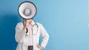 Female doctor in a white coat with a stethoscope, holding a megaphone in front of her face, against a blue background.