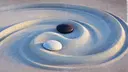 Two small stones, one black and one white, lying in a yin-yang-like arrangement. Circular sand patterns are drawn around them.