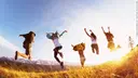 Group of friends running and jumping at a mountain in front of the sunset
