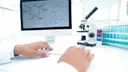 A scientist at a computer in a laboratory, with structural formulas visible on the screen